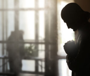Conceptual fine art image of an interior with focus on statue of man praying